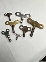 Seven wind-up keys laid out on white surface