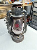 Front view of Dietz Junior railroad lantern showing globe, red lens and frame