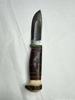 Full view of knife showing blade, stacked leather handle and antler pommel