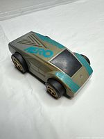 Top/front view showing gray body, teal graphics, wheels