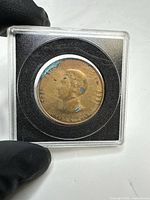 Obverse of bronze token showing Polk bust and 1844 date in plastic holder