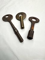 Three brass clock winding keys laid out on white background