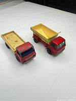 Flatbed and dump trucks side by side showing colours and wear