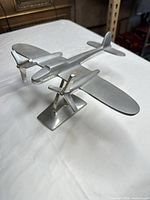Three-quarter front view of cast aluminum airplane sculpture on stand
