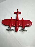 Front view of red cast metal airplane wall hook with silver propellers