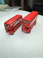 Front and side view of both red diecast buses
