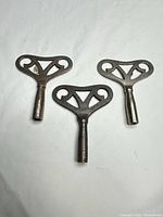 Three matching steel/iron clock winding keys displayed flat
