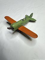 Oblique view of green and orange die-cast airplane showing propeller and fuselage condition