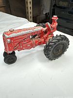 Left side view of red cast iron tractor toy