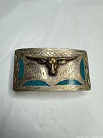 Front view showing full buckle design with bull head and blue inlays