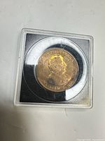 Obverse of bronze token in plastic holder