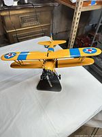 Front three-quarter view of yellow U.S. Navy wooden biplane on stand