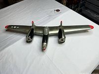 Top view of full airplane showing silver body, twin engines, red tips, insignia