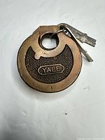 Front view of round Yale brass padlock with keys attached