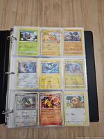 Binder open showing nine Pokémon cards in sleeves