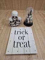 All three items: skull cluster, glass dome skull display, wooden sign