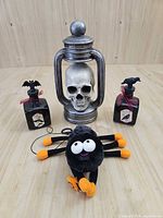 Front view of skull lantern, two bottles, plush spider