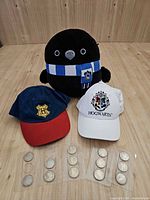 Group shot showing Ravenclaw plush, two Hogwarts caps and 12 coins in sleeves