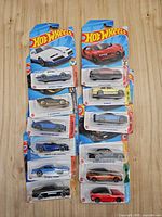 Two columns of twelve Hot Wheels cars in blister packs on a wood background
