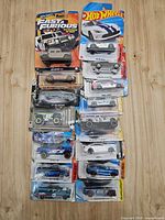 Full view of all 14 carded Hot Wheels cars arranged in two columns on wood surface