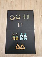All seven earrings pairs displayed on two black boards