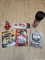 Entire lot laid out: three packaged cars, plush bear, air freshener, travel mug