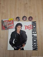 Group shot showing LP jacket, CD case and three buttons