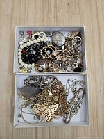 two small boxes filled with assorted gold-tone and silver-tone jewelry pieces