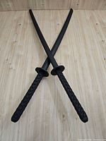 Both black practice katanas crossed showing full view