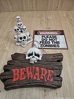 All three Halloween items grouped: Beware sign, stacked skulls, zombie warning plaque