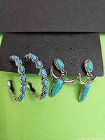 Overview of both cuff bracelets and pair of dangle earrings on display card