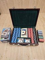 Open wooden case showing chips, card decks, rule booklet, card shuffler box