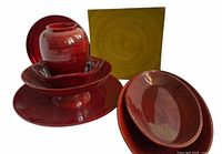 Front angled view showing red vase, bowls, platters and yellow tray