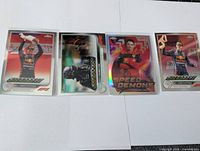 Front view of four featured cards: Verstappen, Hamilton, Leclerc insert, Verstappen variant