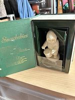 Figurine inside open green Snowbabies box