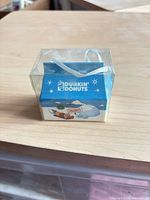 Front view of Dunkin' Donuts winter gift box ornament in plastic cube