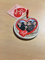 Front of ornament showing characters, heart border, map background, tag visible