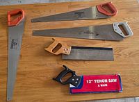 Overall view of five saws laid on wood surface