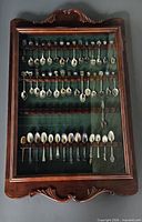 Full front view of closed Bombay Company display case filled with souvenir spoons