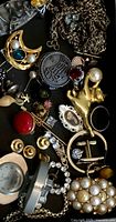 Overview of mixed jewelry showing chains, brooches, bracelet, charms and watch