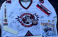 All items laid out: signed jersey, mini stick, puck, armband, program