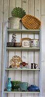 Full view of ladder shelves with assorted pottery, glass and wood pieces
