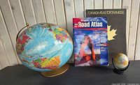 Group shot of both globes and two atlases standing upright