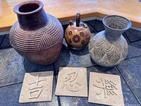 Group shot showing three pottery vessels and three clay tiles