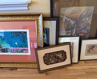Group shot of six framed artworks leaning against wall