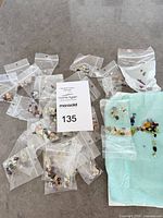 Overview of multiple small baggies with mixed cabochons and MaxSold lot card