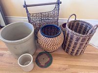 Group shot of all baskets, two stoneware crocks, braided trivet