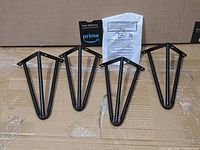 Four black metal furniture legs with packaging