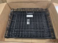 Folded black wire dog crate inside cardboard box