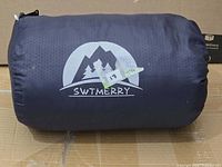 Rolled sleeping bag in stuff sack with brand logo visible
